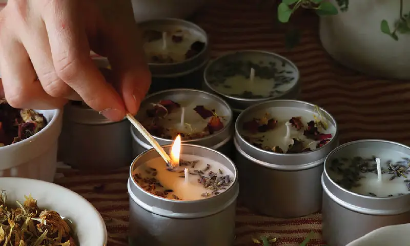 Hand-lighting a mahogany teakwood candle during the handcrafted candle making process