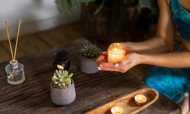 Person holding a mahogany teakwood candle in a calm, cozy home setting