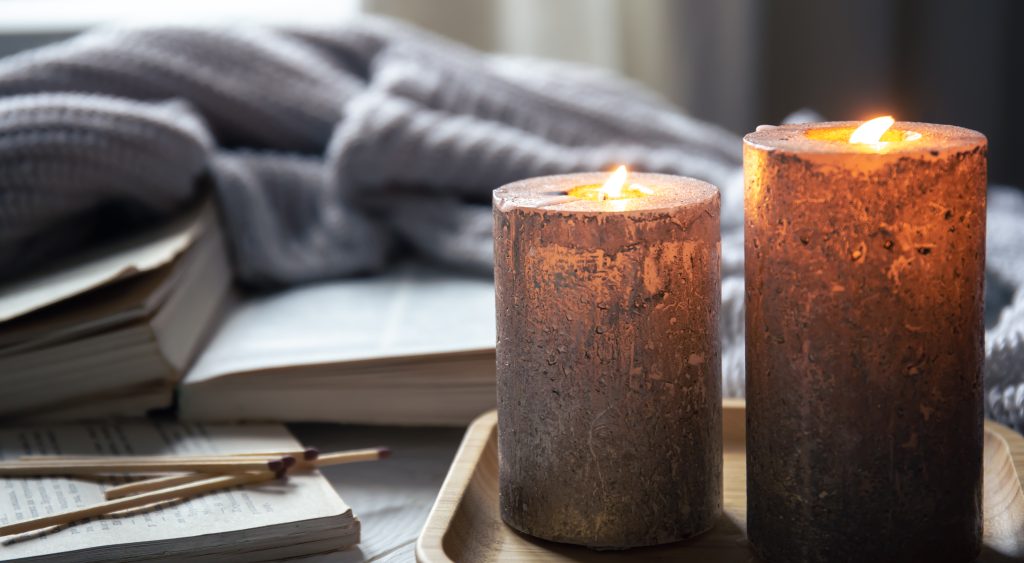 Mahogany teakwood candles glowing in a cozy home setting with warm ambient light